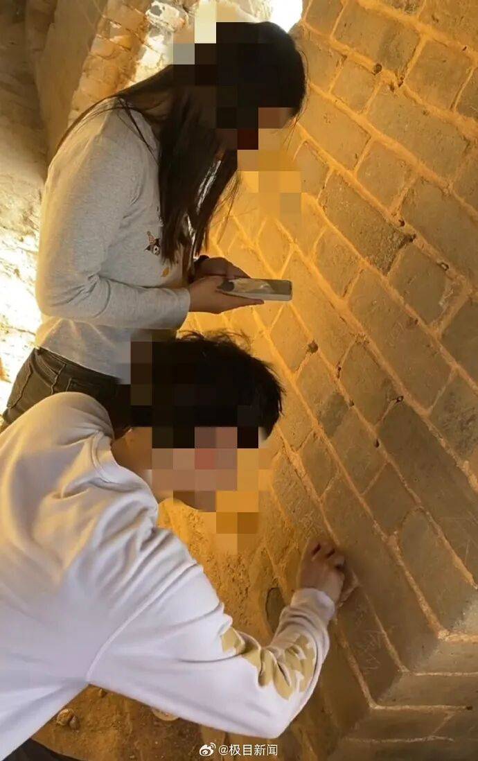 男子在司马台长城墙上刻名字无视劝阻,同行女子拿手机拍照留念